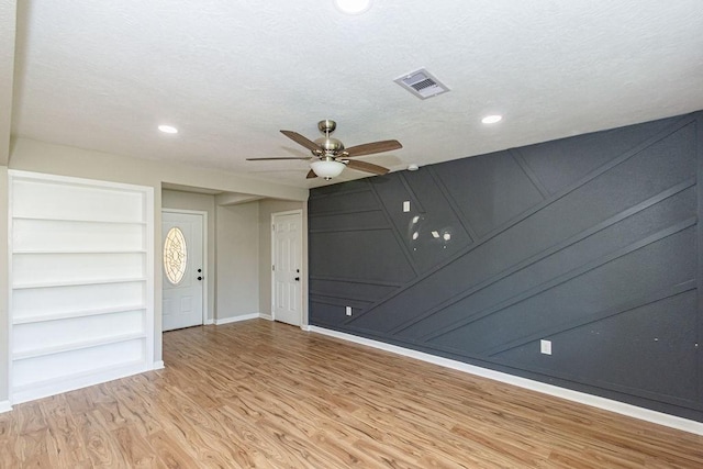 empty room with wood finished floors, a ceiling fan, baseboards, recessed lighting, and built in features