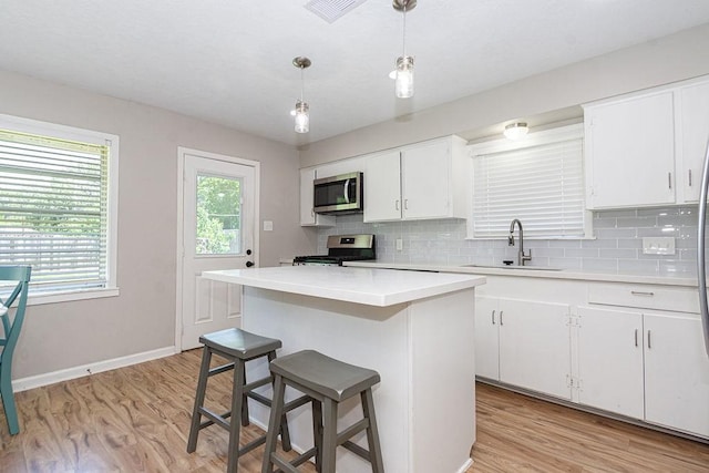 kitchen featuring a sink, stainless steel appliances, light countertops, and tasteful backsplash