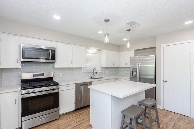 kitchen featuring stainless steel appliances, a sink, light wood-style flooring, light countertops, and recessed lighting