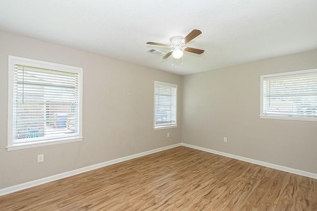 spare room featuring light wood-style flooring, plenty of natural light, and baseboards