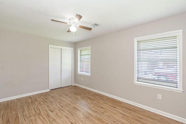 unfurnished bedroom featuring light wood-style flooring, baseboards, a closet, and a ceiling fan