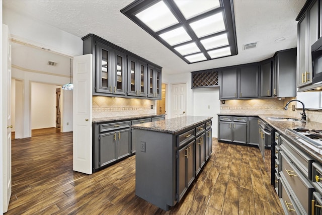 12514 Wealdstone Dr, Tomball, TX 77377 - kitchen featuring dark stone countertops, dark wood-type flooring, a sink, backsplash, and a textured ceiling