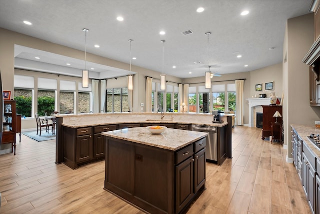 kitchen featuring stainless steel dishwasher, a large island, dark brown cabinetry, light wood-style floors, and recessed lighting