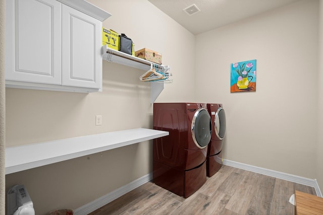 laundry area featuring washer and dryer, baseboards, cabinet space, and light wood-style floors