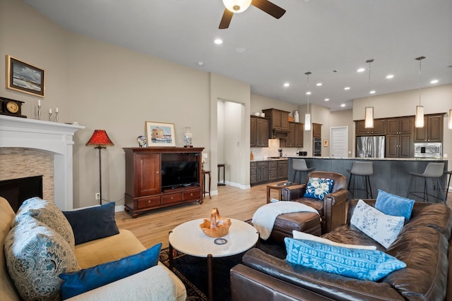 living room with a ceiling fan, light wood-style flooring, baseboards, recessed lighting, and a fireplace