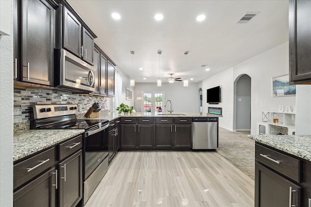 21022 Solstice Point Dr, Hockley, TX 77447 - kitchen with appliances with stainless steel finishes, arched walkways, open floor plan, a peninsula, and a ceiling fan