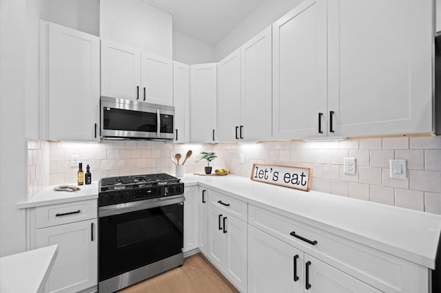 322 Neyland St, Houston, TX 77022 - kitchen featuring stainless steel microwave, black gas stove, light countertops, and white cabinetry