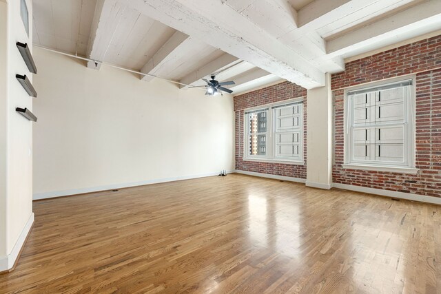 1120 Texas St Unit 7D, Houston, TX 77002 - unfurnished living room featuring baseboards, light wood finished floors, beamed ceiling, brick wall, and a ceiling fan