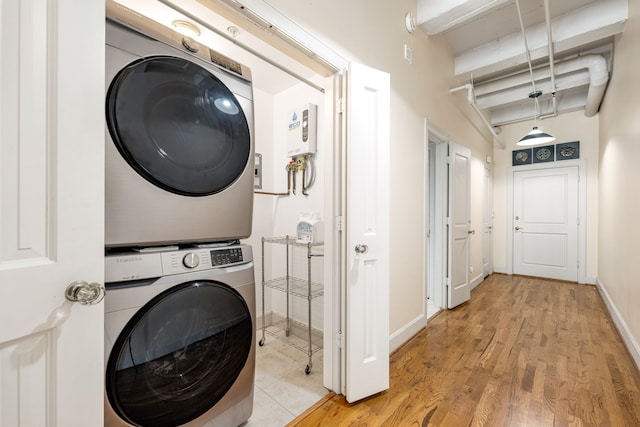 1120 Texas St Unit 7D, Houston, TX 77002 - laundry area featuring stacked washer / dryer, light wood-style floors, and baseboards