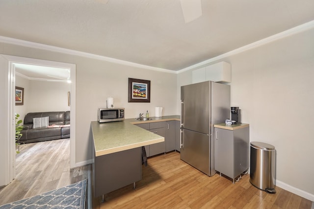 1710 Spring St, Houston, TX 77007 - kitchen with appliances with stainless steel finishes, ornamental molding, light wood-style flooring, gray cabinetry, and a sink
