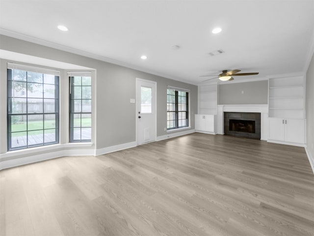 unfurnished living room with a ceiling fan, healthy amount of natural light, baseboards, light wood finished floors, and crown molding