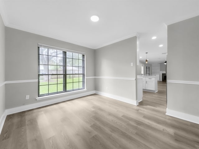 empty room featuring ornamental molding, baseboards, light wood-type flooring, a ceiling fan, and recessed lighting