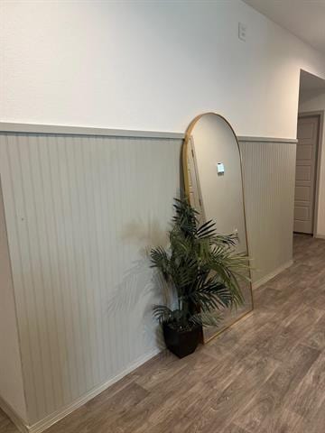 hallway with a wainscoted wall and wood finished floors
