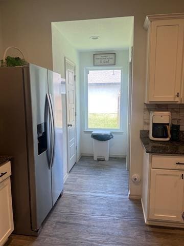 kitchen with stainless steel fridge, white cabinets, and wood finished floors