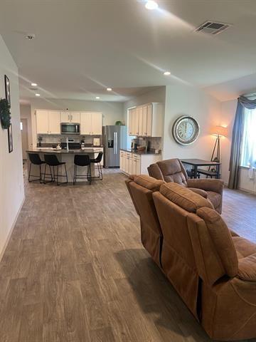 living room with wood finished floors, recessed lighting, and baseboards