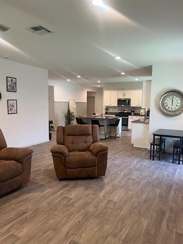 living room with dark wood-style flooring and recessed lighting