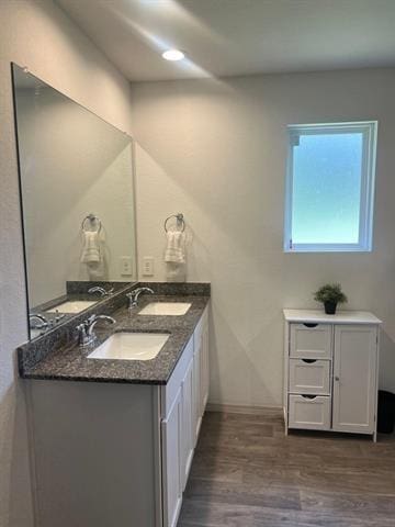 bathroom with wood finished floors, double vanity, and baseboards
