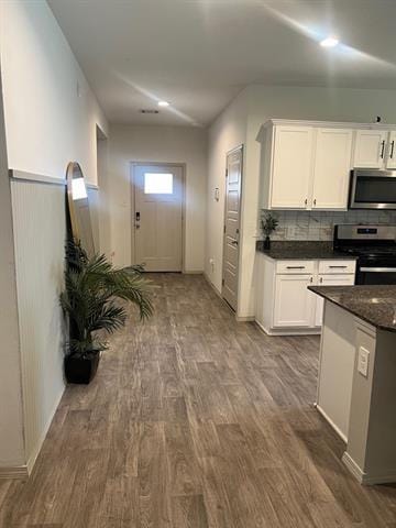 kitchen with stainless steel appliances, white cabinets, dark wood-type flooring, and decorative backsplash