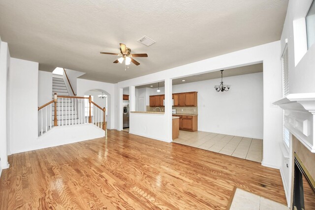 13114 Oak Ledge Dr, Houston, TX 77065 - unfurnished living room with a fireplace, a ceiling fan, stairs, a chandelier, and arched walkways