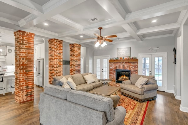 living area featuring french doors, a brick fireplace, healthy amount of natural light, beam ceiling, and coffered ceiling
