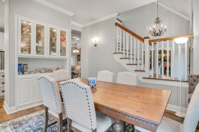 dining area featuring a chandelier, light wood-style flooring, stairs, crown molding, and ceiling fan