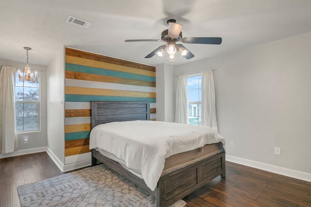 bedroom featuring a chandelier, baseboards, wood finished floors, wooden walls, and ceiling fan