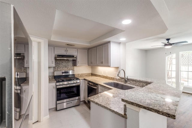 10816 Briar Forest Dr Unit 33, Houston, TX 77042 - kitchen with appliances with stainless steel finishes, a sink, a raised ceiling, a peninsula, and light stone countertops