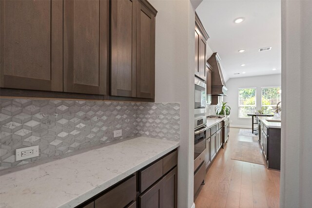 kitchen with light wood finished floors, stainless steel appliances, decorative backsplash, light stone counters, and recessed lighting