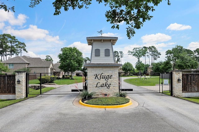 community / neighborhood sign with a gate and a residential view