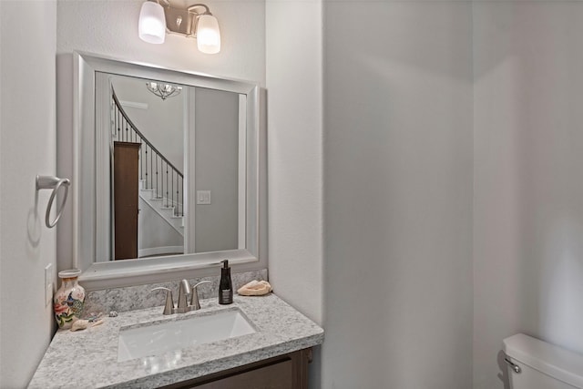 bathroom featuring a chandelier, toilet, and vanity