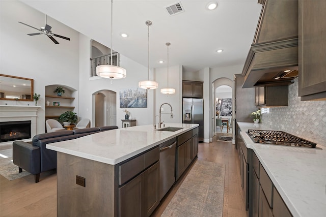 kitchen featuring a sink, arched walkways, appliances with stainless steel finishes, light wood-style floors, and recessed lighting