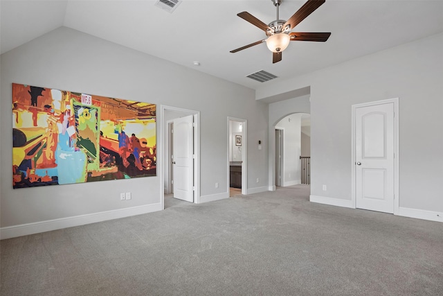 unfurnished bedroom featuring carpet floors, arched walkways, baseboards, vaulted ceiling, and ensuite bathroom