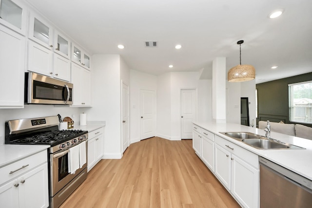 2003 Ballesteros St, Crosby, TX 77532 - kitchen featuring appliances with stainless steel finishes, a sink, light wood finished floors, light countertops, and white cabinets