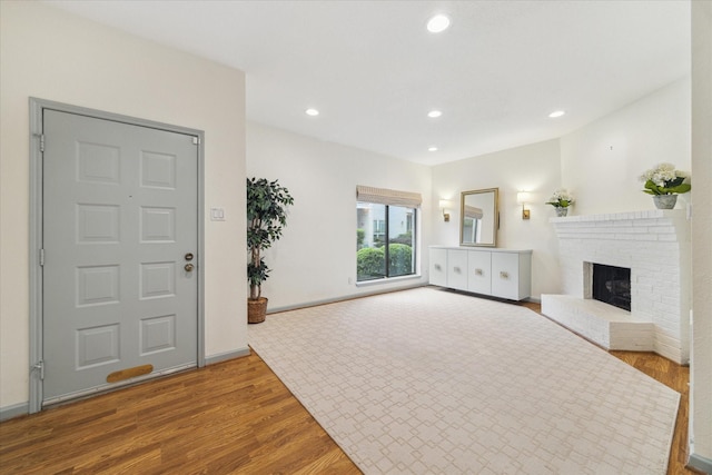 unfurnished living room featuring wood finished floors, recessed lighting, a brick fireplace, and baseboards
