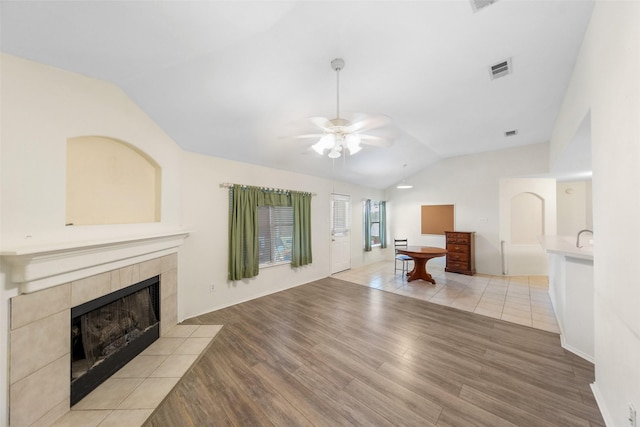 17922 Cypress Valley Ln, Cypress, TX 77429 - unfurnished living room with vaulted ceiling, a tile fireplace, a ceiling fan, and light wood-style flooring