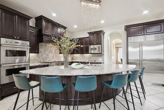3109 Mcculloch Cir, Houston, TX 77056 - kitchen featuring built in appliances, arched walkways, a sink, tasteful backsplash, and recessed lighting