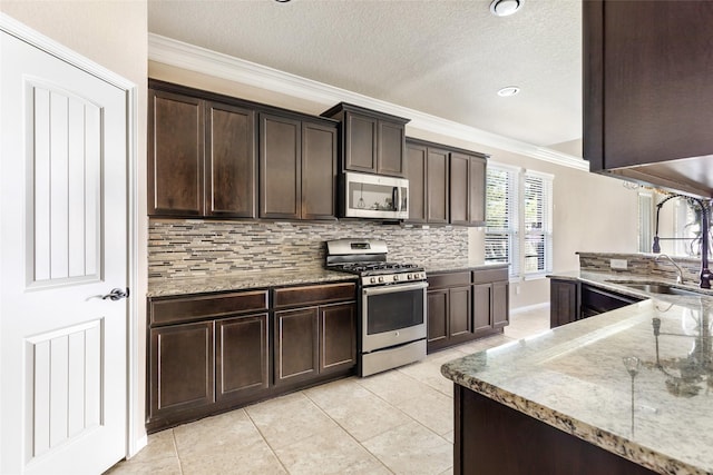 kitchen featuring stainless steel appliances, a sink, ornamental molding, tasteful backsplash, and dark brown cabinetry