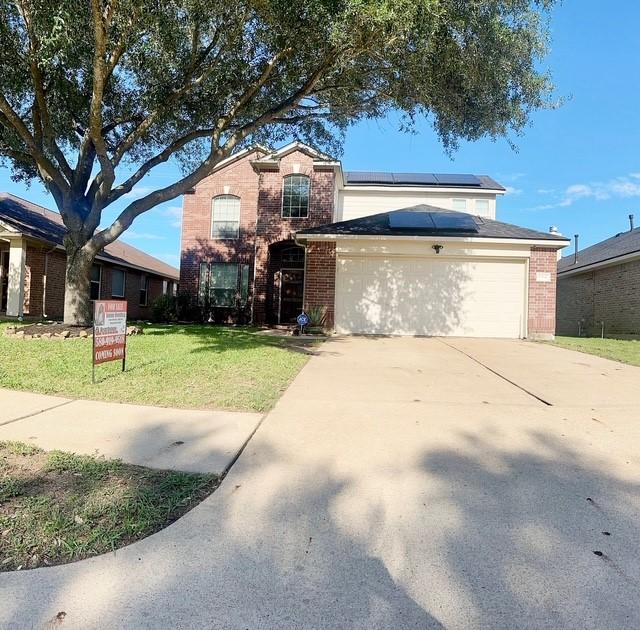 6514 Evening Rose Ln, Katy, TX 77449 - traditional-style house featuring brick siding, roof mounted solar panels, a front lawn, and concrete driveway