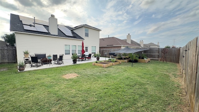 6514 Evening Rose Ln, Katy, TX 77449 - rear view of property featuring a patio area, roof mounted solar panels, a vegetable garden, and a chimney