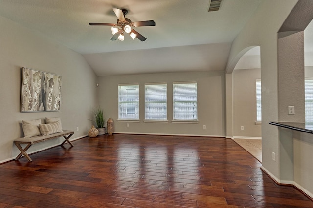 living area with lofted ceiling, ceiling fan, wood-type flooring, arched walkways, and plenty of natural light