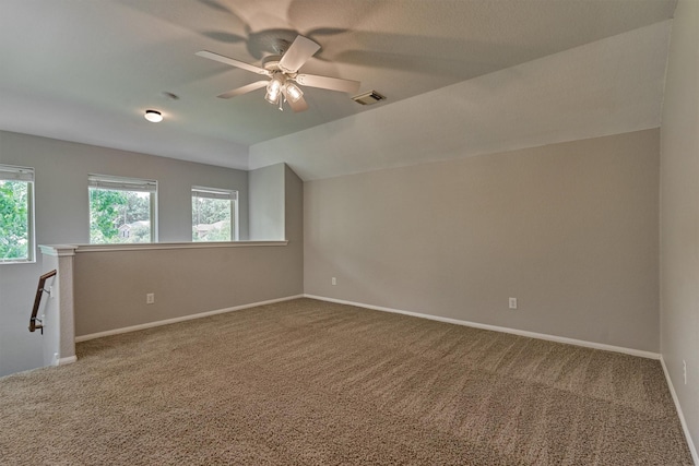 carpeted empty room featuring healthy amount of natural light, a ceiling fan, lofted ceiling, and baseboards