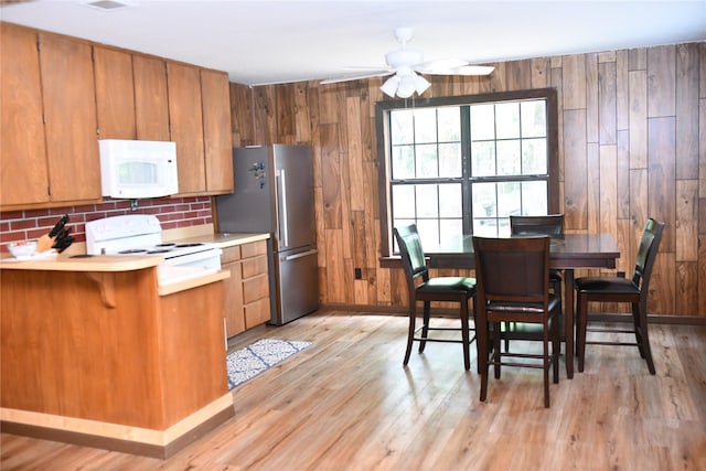 112 Lcr 902, Jewett, TX 75846 - kitchen featuring white appliances, light countertops, brown cabinetry, light wood-style floors, and wood walls