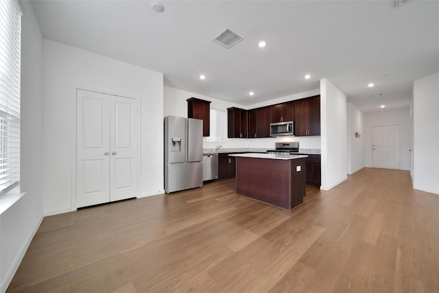 23431 Wrexham St, Spring, TX 77373 - kitchen with appliances with stainless steel finishes, light wood-style floors, dark brown cabinetry, a kitchen island, and light countertops