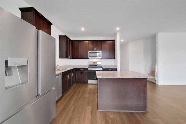 23431 Wrexham St, Spring, TX 77373 - kitchen with stainless steel appliances, a sink, light wood-style floors, a kitchen island, and dark brown cabinetry