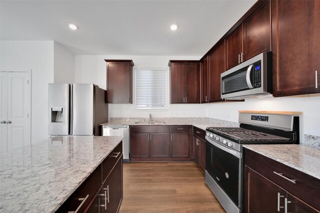 23431 Wrexham St, Spring, TX 77373 - kitchen featuring stainless steel appliances, light stone countertops, a sink, wood finished floors, and dark brown cabinets