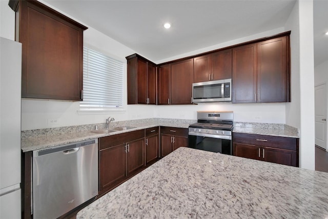 23431 Wrexham St, Spring, TX 77373 - kitchen featuring stainless steel appliances, a sink, light stone counters, dark brown cabinetry, and recessed lighting