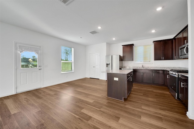 23431 Wrexham St, Spring, TX 77373 - kitchen with appliances with stainless steel finishes, a kitchen island, dark brown cabinetry, dark wood-style flooring, and a sink