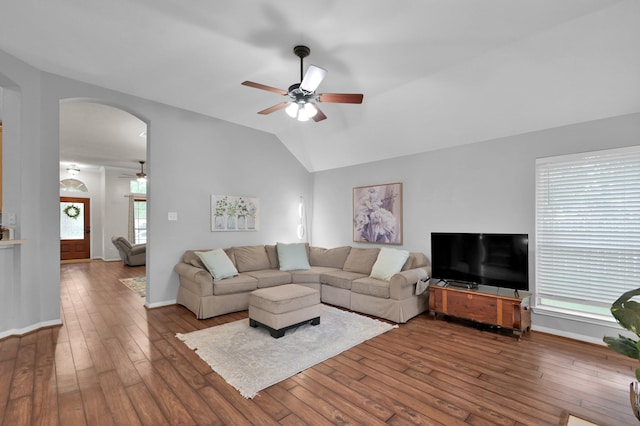living room with a ceiling fan, arched walkways, vaulted ceiling, wood-type flooring, and baseboards