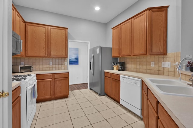 kitchen with stainless steel appliances, a sink, light countertops, tasteful backsplash, and light tile patterned floors