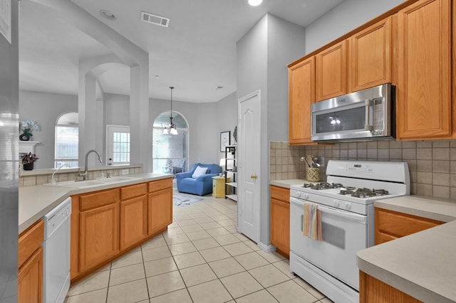 kitchen featuring white appliances, a sink, tasteful backsplash, and light countertops